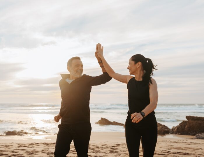 Cheerful mature european couple jogging, give high five, enjoy workout together in morning