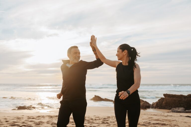 Cheerful mature european couple jogging, give high five, enjoy workout together in morning