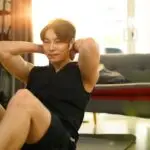 Strong asian man wearing sporty clothes doing sit up exercise during home workout.