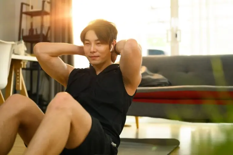 Strong asian man wearing sporty clothes doing sit up exercise during home workout.